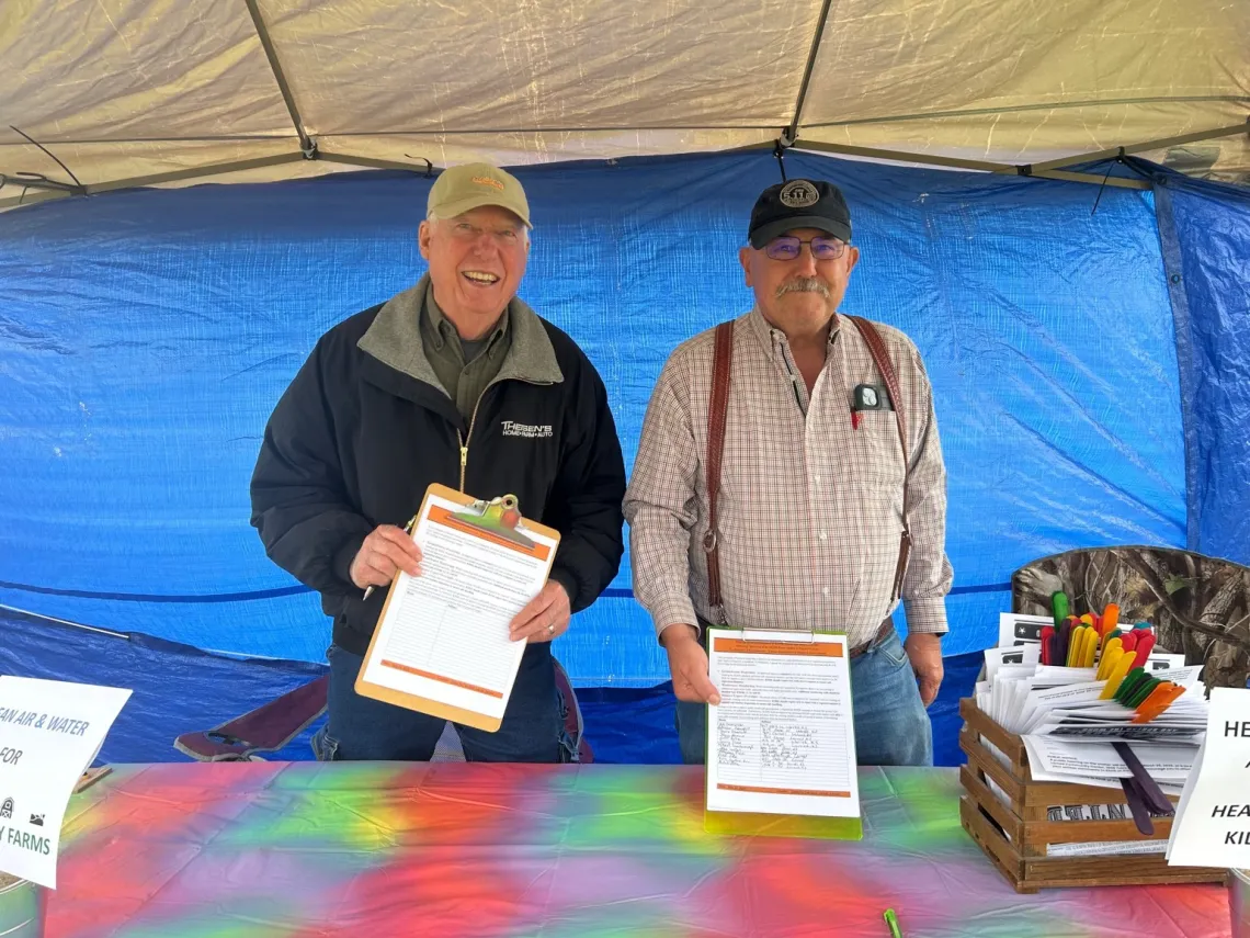 two men in a tent with petitions on clipboards