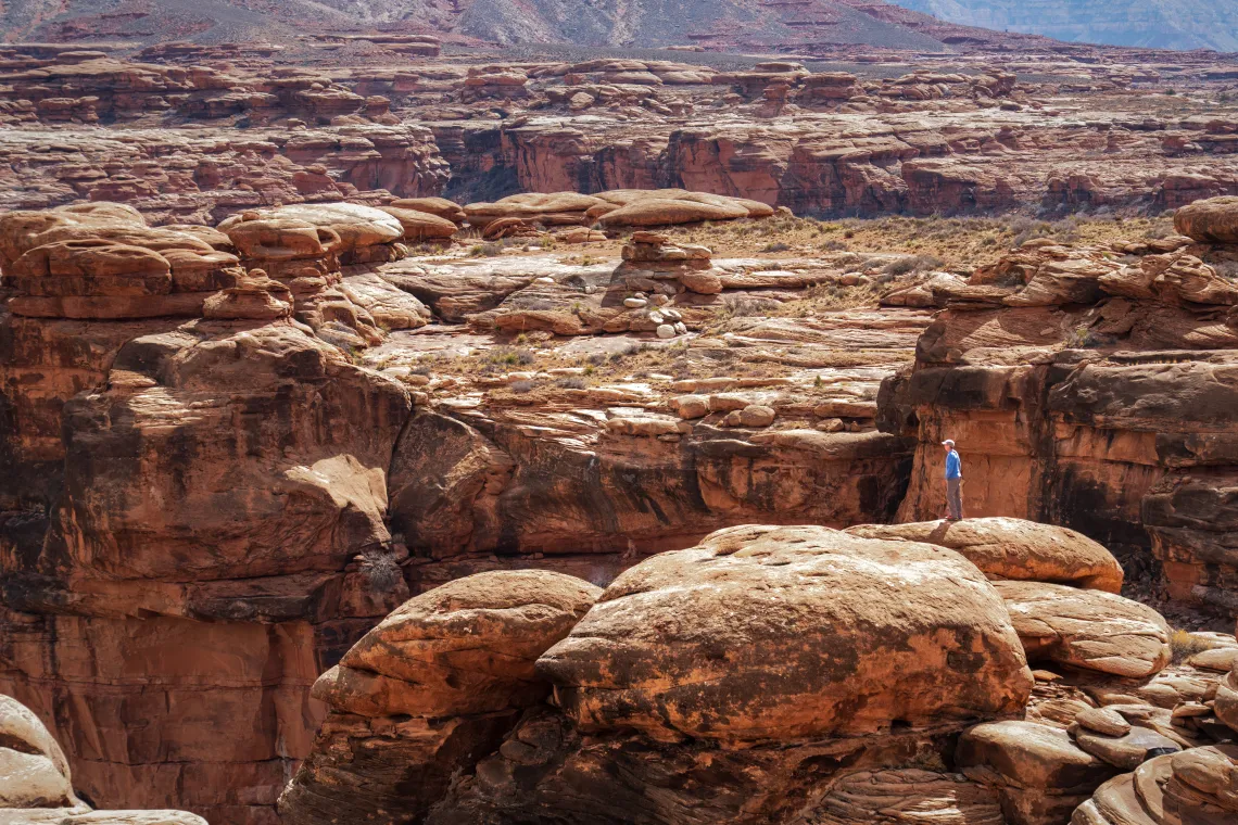 A person stands on top of large, red rocks at Baaj Nwaavjo I'tah Kukveni-Ancestral Footprints of the Grand Canyon National Monument in Arizona.