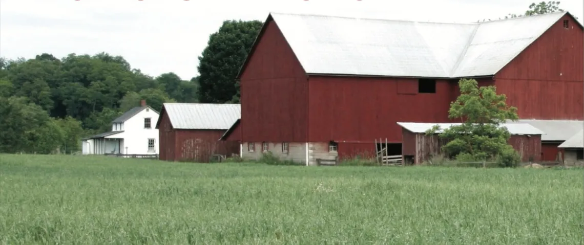 Photo of red barn and white farmhouse across a green field