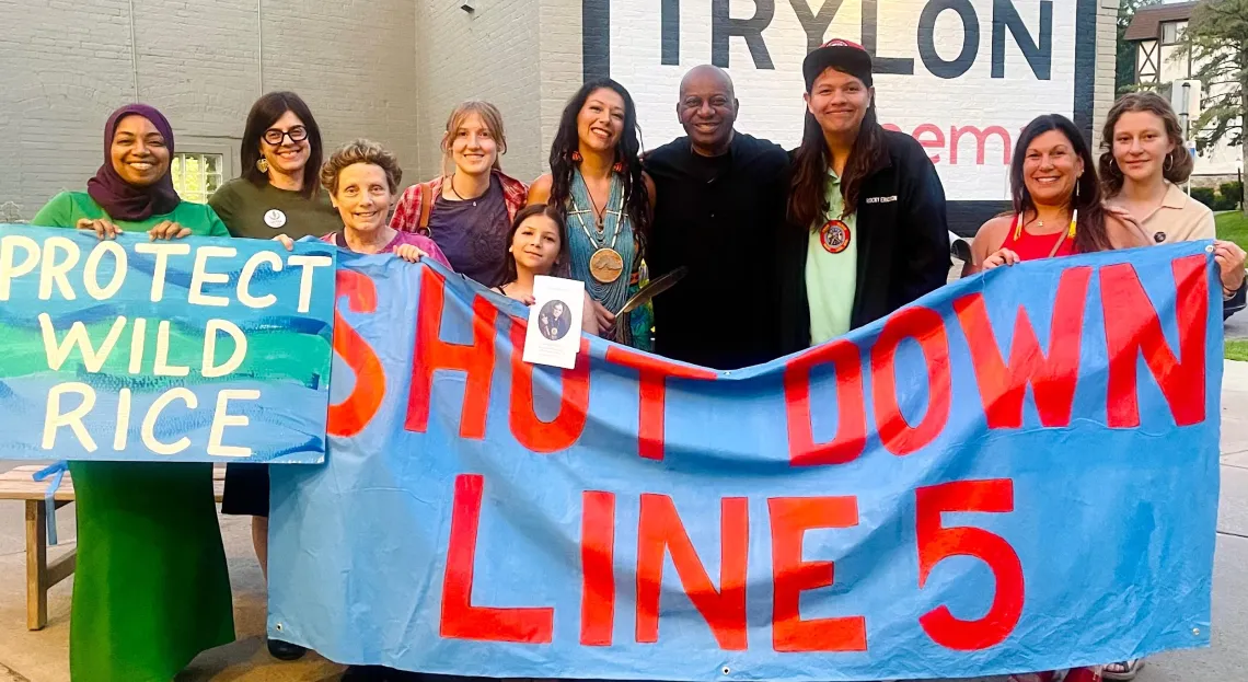 Group with banner the reads "Shut Down Line 5" and "Protect Wild Rice"
