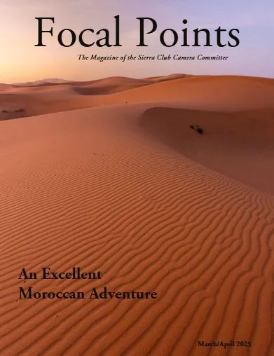 Rippling sand dunes captured in worm pre-dawn light in the foreground receding in graceful curves to the hills in the backgroung under a  blue and gold sky.