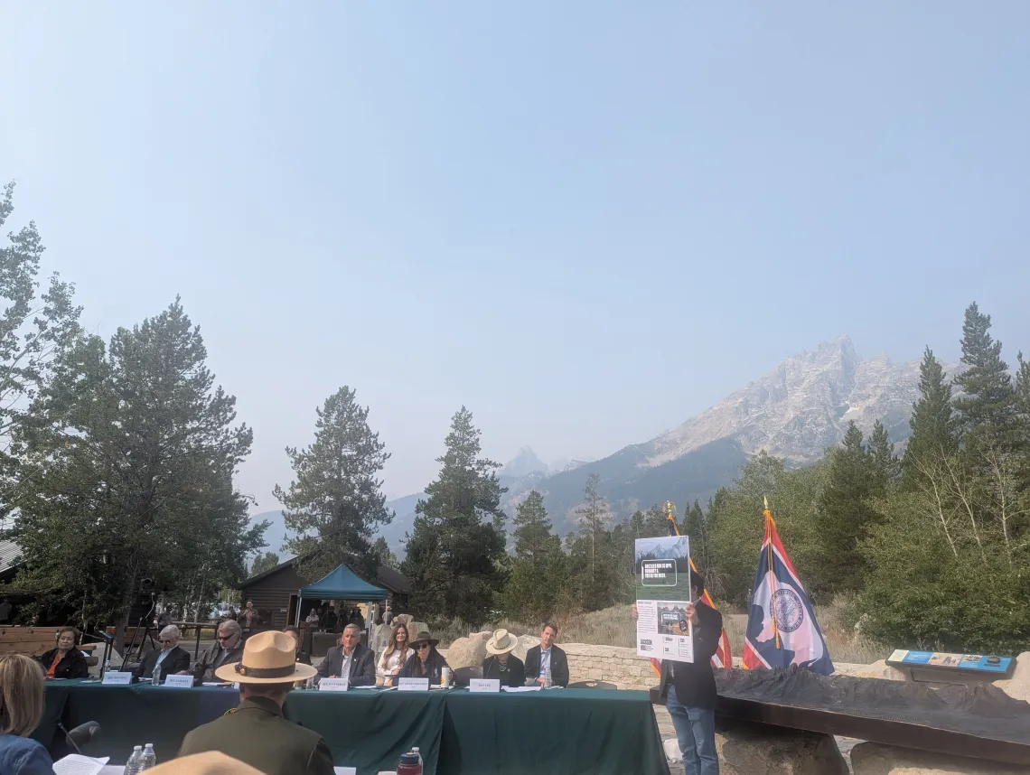 A gathering of people in front of the towering Grand Teton