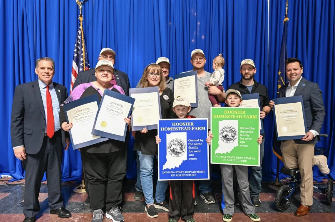 A group of around 10 people holding up awards. They are indoors and there is a blue curtain behind them. 