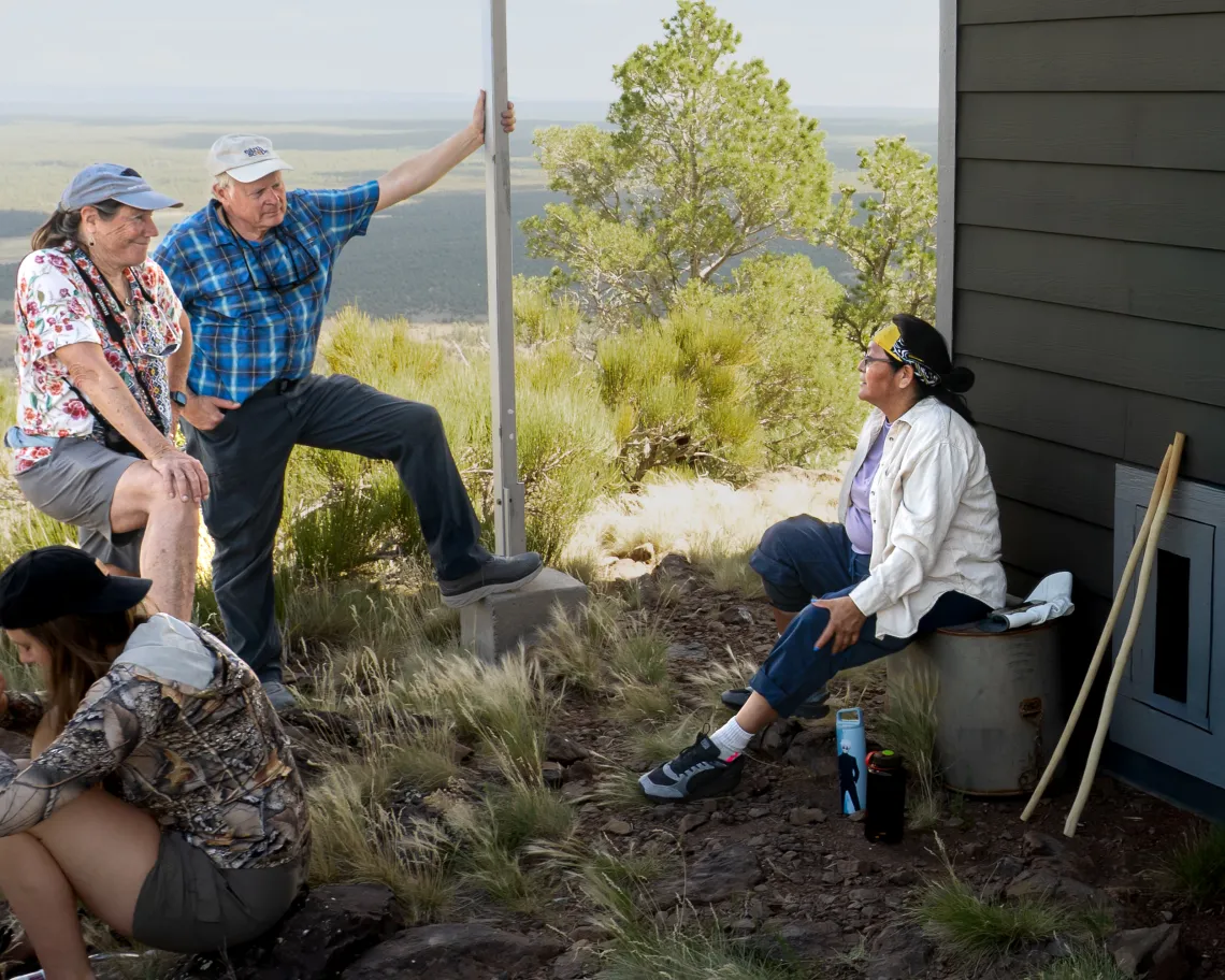three people chatting atop a mountain