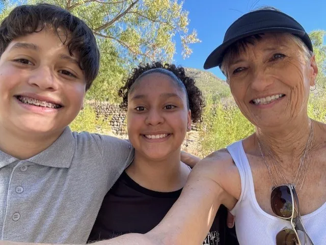Young boy and girl with adult woman all smiling in the camera.