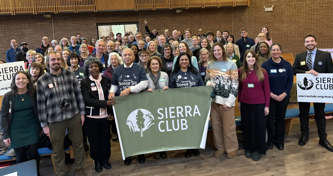 image of people posing for a photo holding Sierra Club signs. 