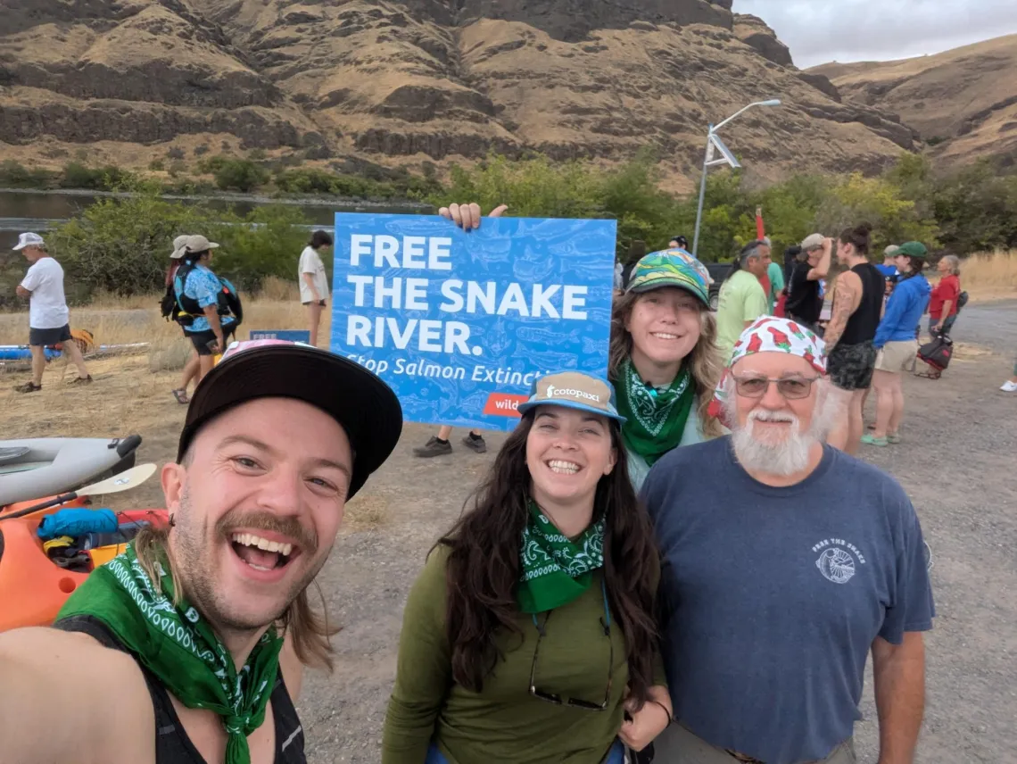 A photo of four people smiling at the camera and holding a sign that reads, Free the Snake River