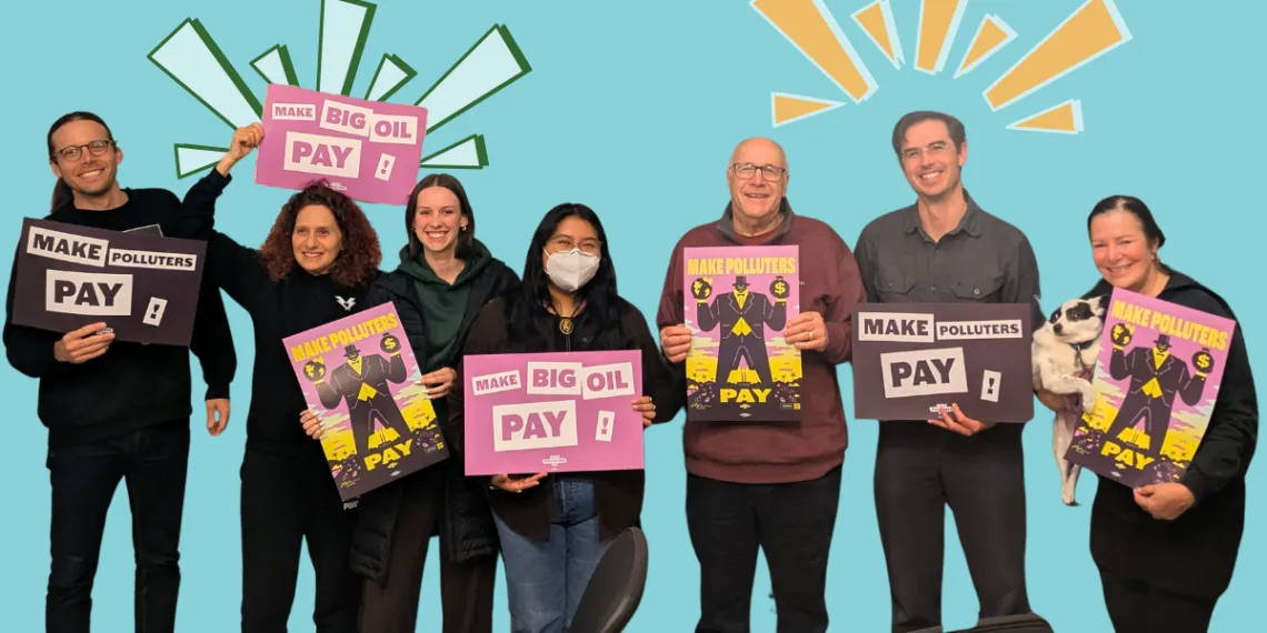 A group of volunteers look at the camera smiling and holding signs