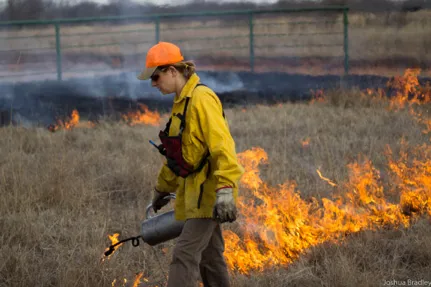 A woman conducting a prescribed burn.