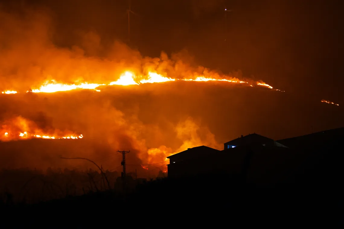 A large grass fire on a hill.