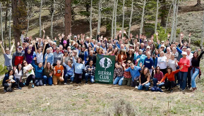 Large group of leaders, holding a Sierra Club Outings flag