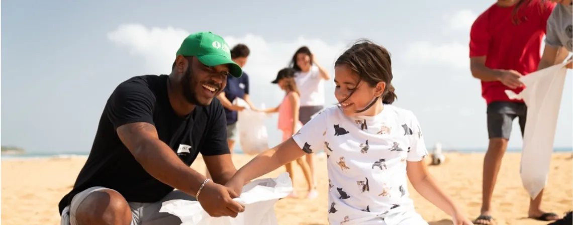 father and daughter picking up trash on the beach