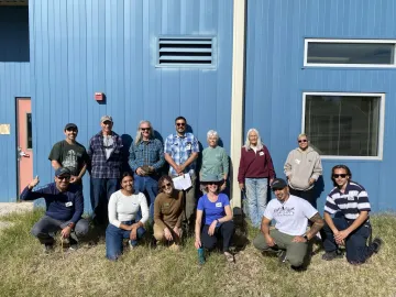 Photo of a group of people smiling in front of a building