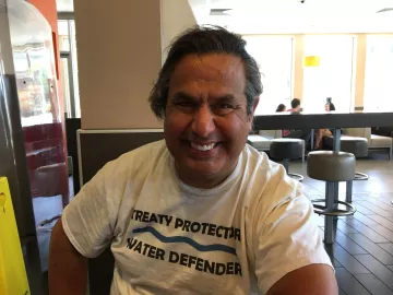 Julian smiling while wearing a shirt that says treaty protectors, water defenders