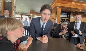 Canadian Prime Minister Justin Trudeau stops a moment to speak with La Coalition Rail Safety Campaign member's son, Carl Zarling, in the rebuilt Music Cafe following mass as Trudeau attends Lac-Mégantic's 10th Anniversary Memorial March.