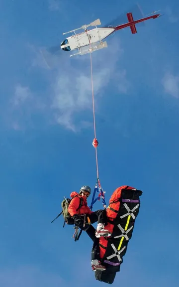 A member of the Grand Teton National Park Search & Rescue team aids a backcountry snowboarder with a broken leg.&nbsp;