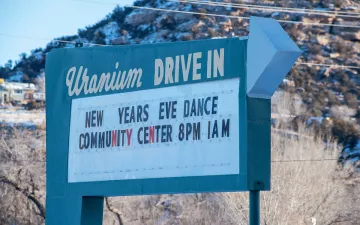 A sign in Nucla reads "Uranium Drive In / New Years Eve Dance / Community Center 8PM 1 AM"
