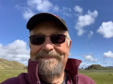 Chapter Outings chair Art Westerfield, wearing a hat and sunglasses standing in front of green hills.
