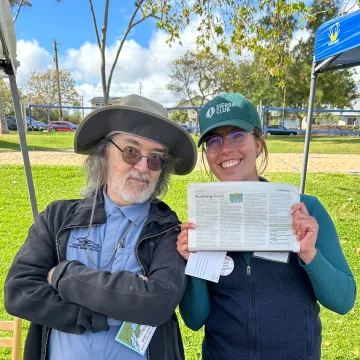 Gianna Patchen and Andrew Christie in a park holding the New Times with their first Down to Earth column