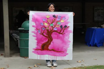 Artist in Residence Kristy Sandoval holds up the community mural