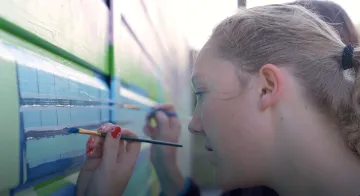 Picture of a girl painting a solar panel on a mural
