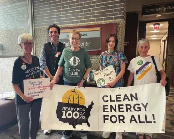 Sierra Club staff and volunteers gather outside a Rochester city council meeting on the 100% goal.