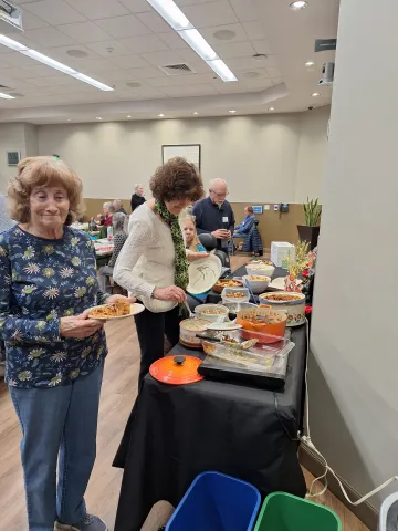 People filling plates at the general meeting potluck