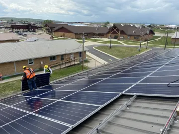 Picture of people installing solar panels on the roof of a school