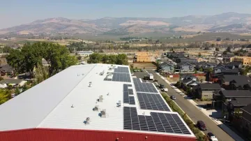 Picture of solar panels on top of a large building with mountains in the background