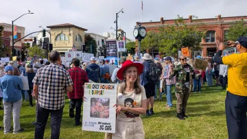Female protester wearing a red hat at the No Kings 3 rally in San Luis Obispo