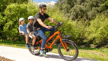 man riding ebike with 2 children on back