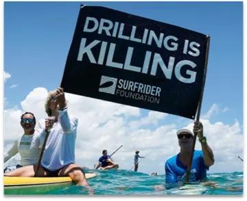 Photo of Surfers displaying sign "Drilling is Killing"