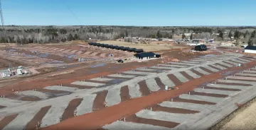 Numerous concrete pads are built on the ground in three long rows, where housing will be set up.