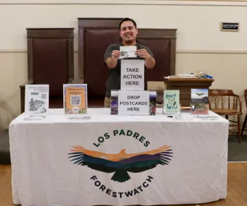 Photo of a man behind a table collecting comments on protecting forests
