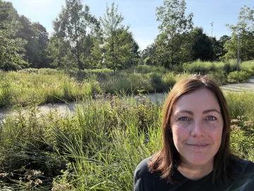 Sierra Club member Meghan Olis poses in front of native plants during a walk at the NC Museum of Art