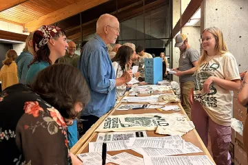 Roadless Rally attendees speak to a Sierra Club staff member at a table with guidance about submitting comments