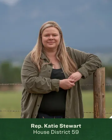 Headshot of Katie Stewart leaning on a wooden fence post 