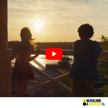 YouTube thumbnail showing two children looking out over a waterway. A red play button is at the center.