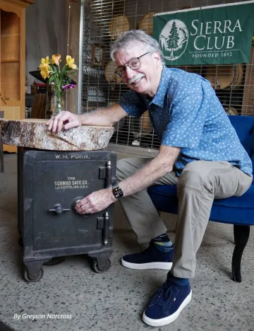 Dave Keesee poses next to an antique safe, with the Sierra Club banner in the background
