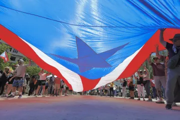 Flag of Puerto Rico held in the air by people