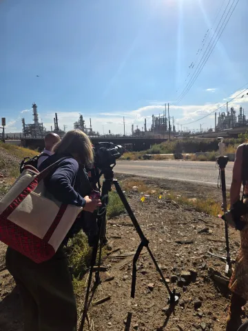 Passengers on the tour look through a camera to see a methane plume not visible to the naked eye at Suncor Refinery.