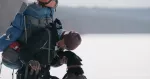 hiker with large pack bent over petting dog