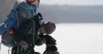 hiker with large pack bent over petting dog