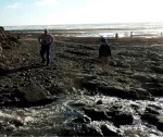 Two people exploring on beach, sun on ocean in background