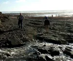 Two people exploring on beach, sun on ocean in background