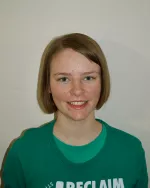 Picture of Anise in front of a white wall, green t-shirt