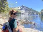 Picture of Jennifer sitting by a lake and mountain