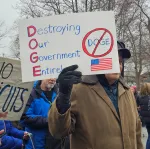 Person holding sign saying DOGE