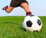 Soccer ball being kicked on bright green natural turf