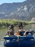 A teenage girl paddling on a giant raft in a river 